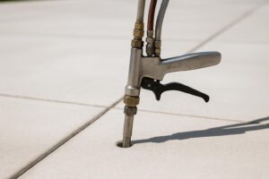 Close-up of polyurethane foam injection equipment repairing a concrete sidewalk, highlighting the clean, minimally invasive process without people or heavy machinery.